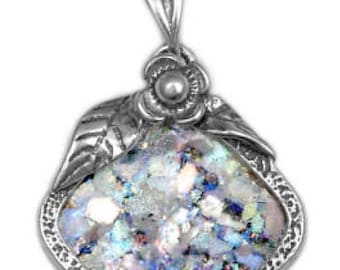 May include: A silver pendant necklace with a square-shaped Roman glass piece set in a silver frame. The glass is iridescent and has a variety of colors, including blue, green, and white. The pendant is attached to a silver chain.