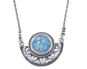 May include: A silver necklace with a blue and green glass pendant set in a filigree design.