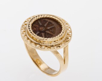 May include: A gold ring with a detailed filigree design. The ring features a round bezel with a dark brown coin inside.