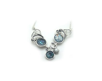 May include: A silver necklace with a V-shaped design featuring four round blue glass stones and a single white pearl.