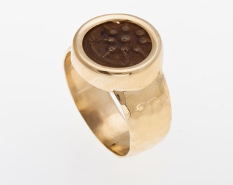 May include: A gold ring with a round, brown stone set in a bezel. The stone has a design of a wheel with spokes.
