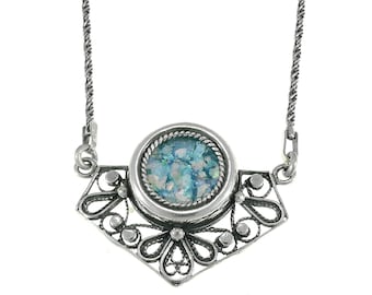 May include: A silver necklace with a delicate filigree pendant featuring a round blue and green glass mosaic.