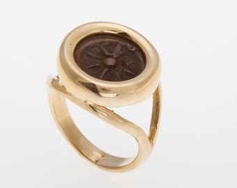 May include: A gold ring with a round bezel set with an antique coin. The coin has a circular design with a star in the center.