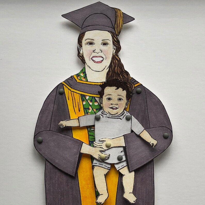 May include: A woman wearing a purple graduation gown and a black cap holds a young child in her arms. The child is wearing a white shirt and has a happy expression on their face.