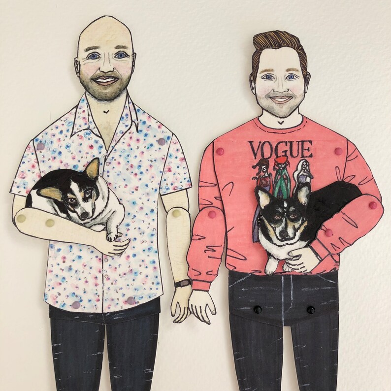May include: Two illustrated paper dolls, one wearing a pink shirt with the word "VOGUE" and the other wearing a pink and white patterned shirt. Both dolls are holding a dog.