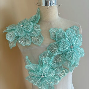 Pu&ograve; includere: Tre applicazioni floreali di colore turchese con paillettes e strass, perfette per aggiungere abbellimenti a vestiti o artigianato.