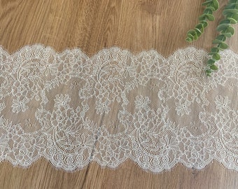 May include: White lace trim with a delicate floral pattern. The lace has a scalloped edge and is perfect for adding a touch of elegance to any project.