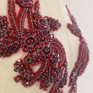 Puede incluir: Aplique de cuentas rojas con un diseño floral. El aplique está hecho de pequeñas cuentas rojas y diamantes de imitación, y tiene un diseño delicado e intrincado.