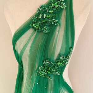 May include: Green sheer fabric with two beaded floral appliques. The appliques are made with green and clear rhinestones.