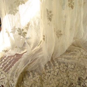May include: White sheer curtains with delicate floral embroidery. The curtains are gathered at the bottom, creating a soft, flowing look.