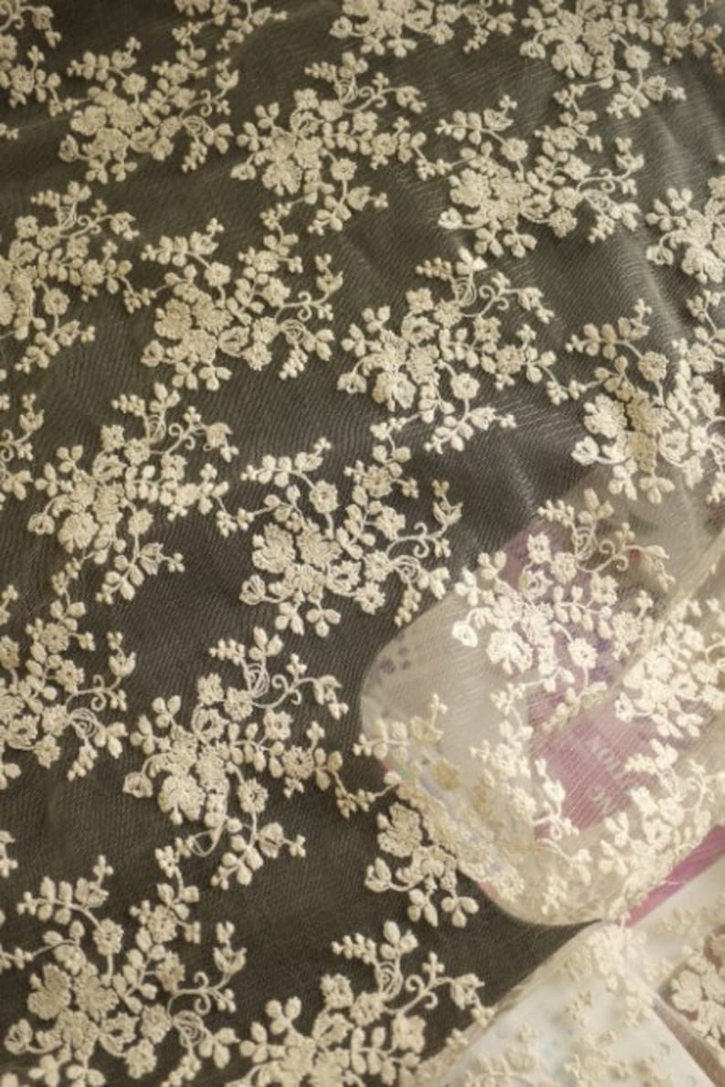 Puede incluir: Tela de encaje floral blanca con un patr&oacute;n delicado. El encaje es transparente y tiene un tacto suave y rom&aacute;ntico.