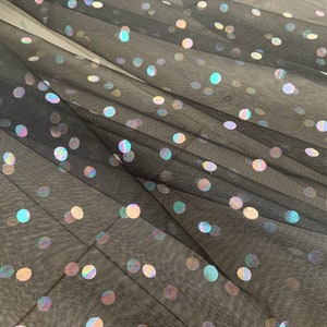 May include: Black sheer fabric with iridescent polka dots. The fabric is translucent and the dots are scattered randomly across the surface.