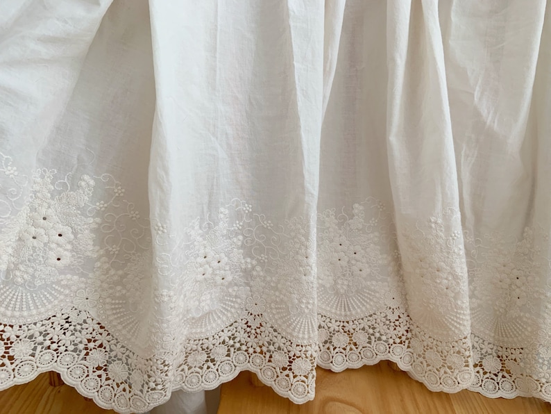 May include: White cotton bed skirt with a delicate white lace trim and embroidered floral details.