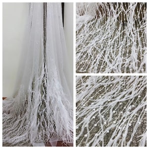May include: White tulle fabric with a delicate feather trim and small white sequins. The fabric is sheer and has a soft, flowing texture.