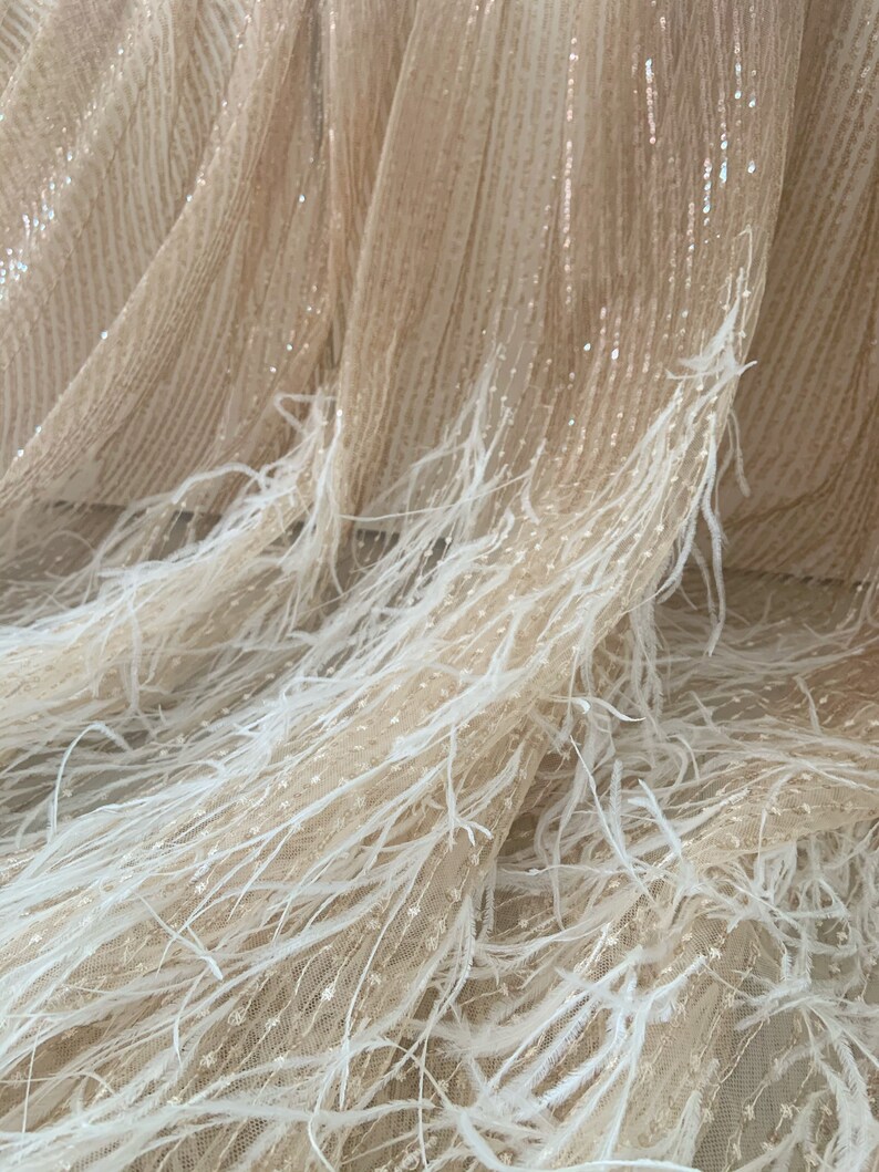 K&ouml;nnte beinhalten: Beige T&uuml;llstoff mit wei&szlig;em Federnbesatz. Der Stoff hat einen dezenten Schimmer und ist perfekt, um einen glamour&ouml;sen Look zu kreieren.