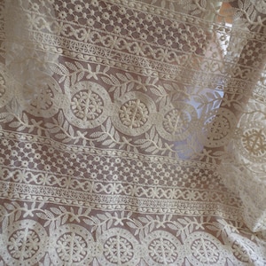 Peut inclure: Tissu de dentelle blanche avec un motif floral d&eacute;licat. La dentelle pr&eacute;sente un motif r&eacute;p&eacute;titif de petites fleurs et de feuilles, cr&eacute;ant un look d&eacute;licat et f&eacute;minin.