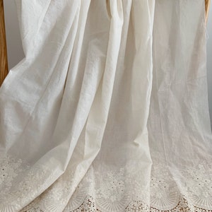 May include: White cotton fabric with a delicate lace trim. The lace features a floral design with small circles and scalloped edges.