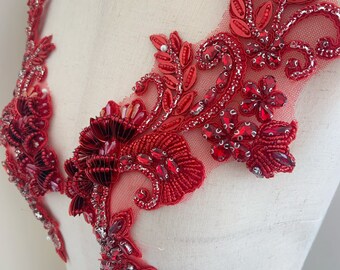 May include: Red beaded and sequined applique with a floral design. The applique is on a sheer fabric background.