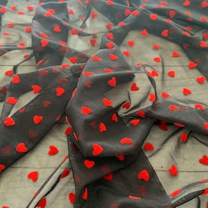 May include: Black mesh fabric with red velvet hearts. The fabric is sheer and has a delicate texture.