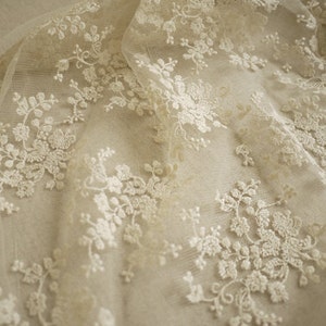 Puede incluir: Tela de encaje floral blanca con un patr&oacute;n delicado. El encaje es transparente y tiene un tacto suave y rom&aacute;ntico.