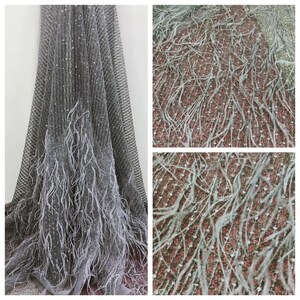 May include: Gray tulle fabric with silver sequins and white feather trim. The fabric is soft and delicate, and the feathers add a touch of elegance.