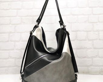 May include: A black, gray, and white color-block shoulder bag with a zipper pocket and adjustable straps. The bag has a convertible design, with straps that can be adjusted to be worn as a backpack.