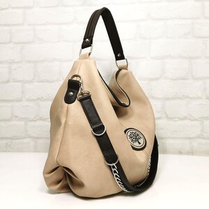 Peut inclure: Sac hobo beige avec une bandouli&egrave;re et une poign&eacute;e noires. Le sac pr&eacute;sente un logo d'arbre &agrave; l'avant et une cha&icirc;ne argent&eacute;e sur la bandouli&egrave;re. Le sac a un design souple et ample.