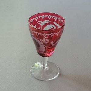 May include: A clear glass stemmed shot glass with a red base and white etched floral design.
