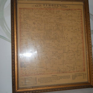 May include: A framed vintage map of Virgil Township, with detailed cartography and text. The map is encased in a gold-colored wooden frame, adding a classic aesthetic. The map's aged paper has a sepia tone, and the text is in black.