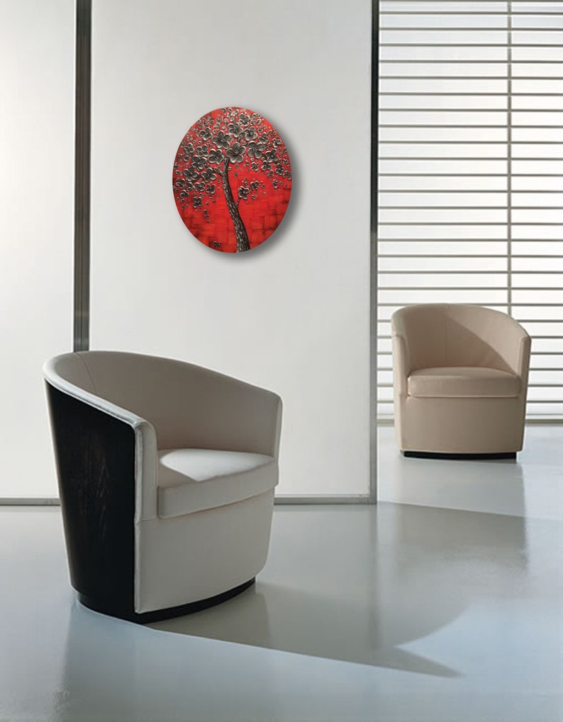 May include: A round wall art piece featuring a black tree with white flowers on a red background.