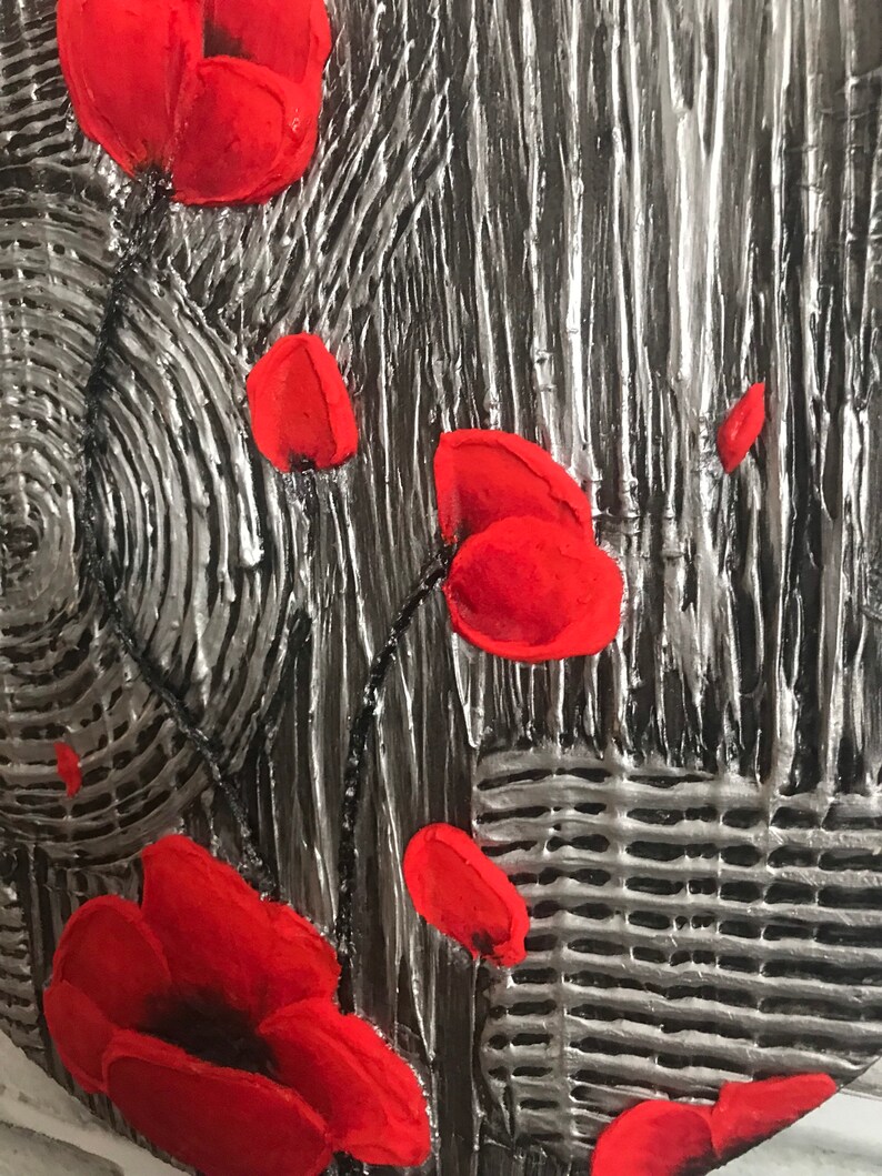 May include: Close-up of a textured artwork featuring bright red poppy flowers against a silver and gray background. The painting has a raised, three-dimensional effect, with visible brushstrokes and a textured surface.