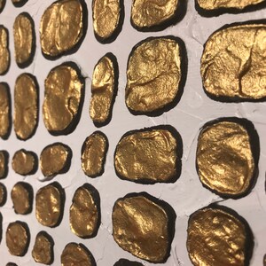 May include: A white background with a pattern of gold painted circles. The circles are outlined in black and have a textured surface.