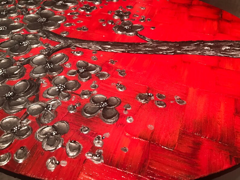 May include: A red and silver abstract painting featuring a stylized tree with black flowers. The background is a textured red with a silver metallic sheen.