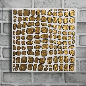 May include: A square canvas painting with a textured gold and white pattern. The pattern resembles a crocodile skin.