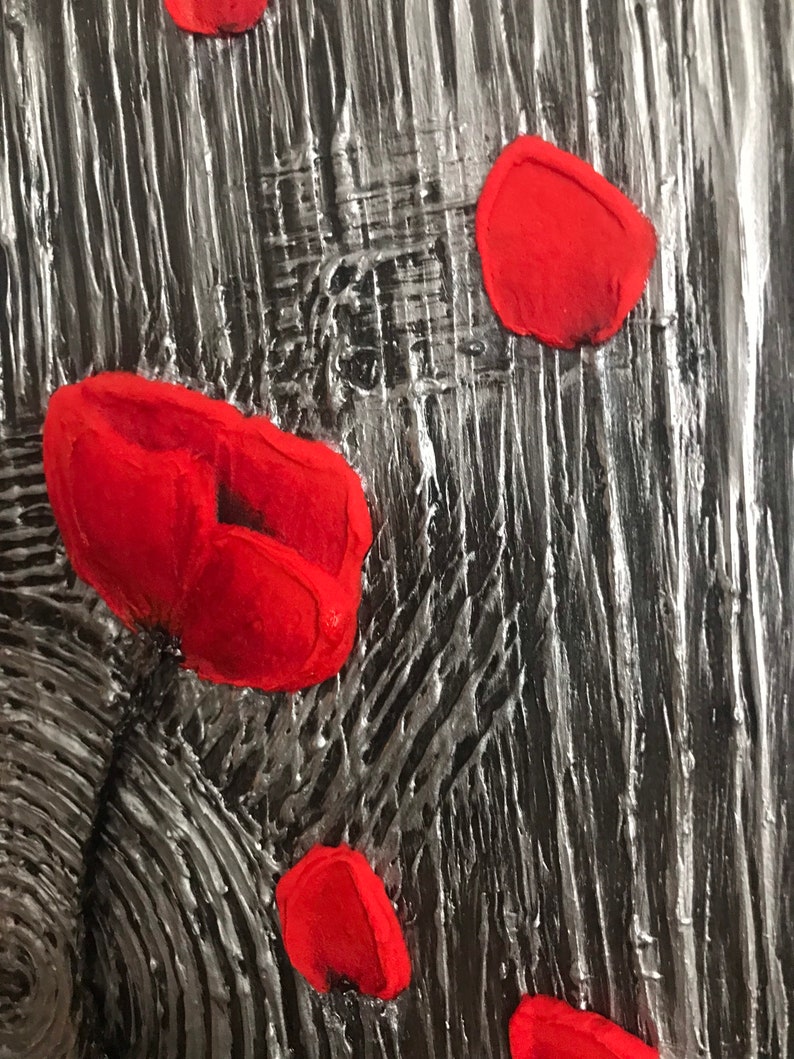 May include: Abstract textured artwork with a black and silver background. Several bright red, petal-shaped elements are scattered across the surface, creating a striking contrast. The piece has a rough, tactile quality.