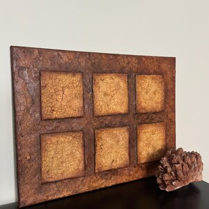 K&ouml;nnte beinhalten: Ein rechteckiges Wandbild mit rustikalem, strukturiertem Design. Das St&uuml;ck besteht aus sechs Quadraten, jedes mit einem anderen Muster aus Rissen und Linien. Die Quadrate sind von einem braunen Rahmen umgeben.
