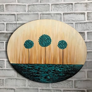May include: A round wooden canvas painting with a teal blue water scene and three teal blue trees. The trees are stylized and have a textured look.