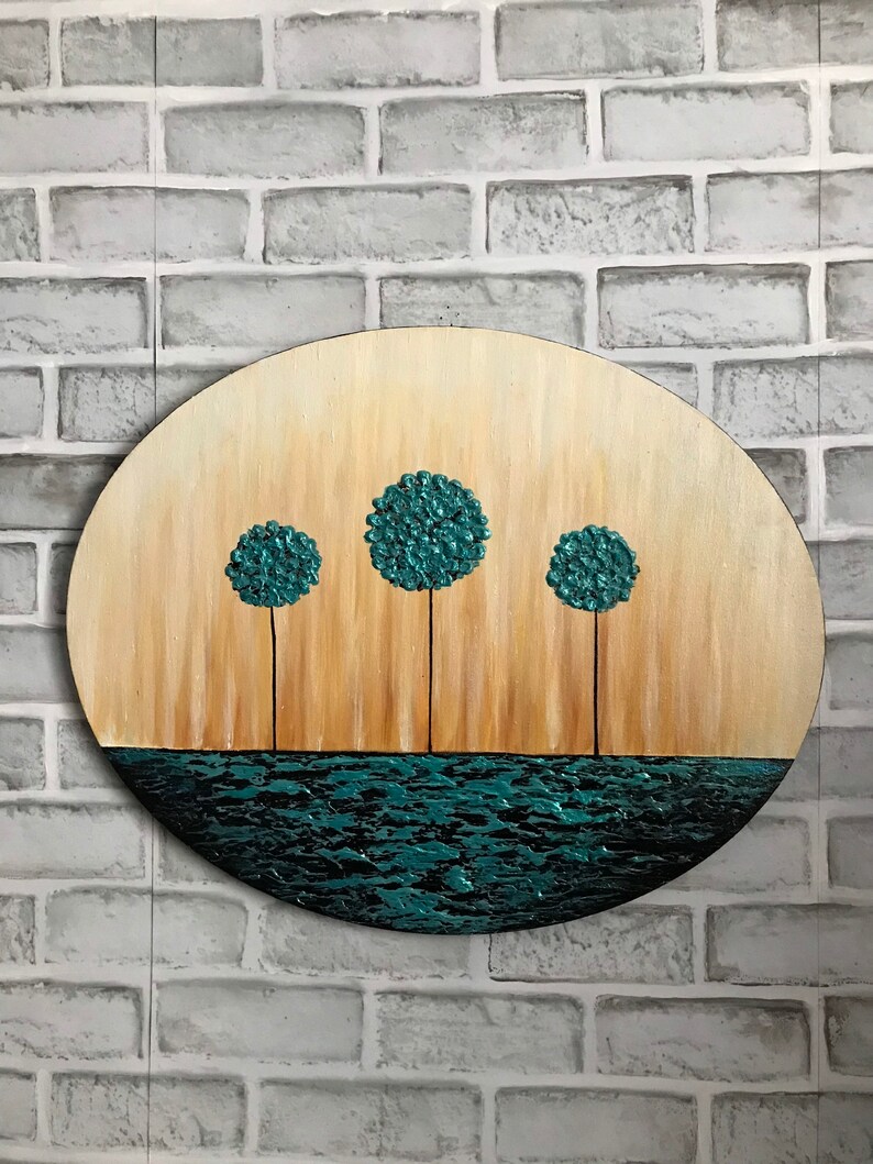 May include: A round wooden canvas painting with a teal blue water scene and three teal blue trees. The trees are stylized and have a textured look.
