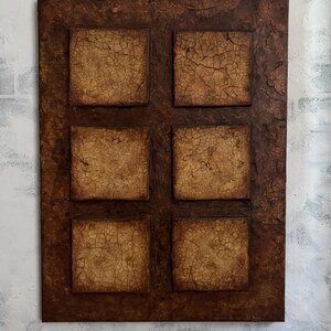K&ouml;nnte beinhalten: Eine braune rechteckige Leinwand mit sechs quadratischen Paneelen. Jedes Paneel hat eine strukturierte, rissige Oberfl&auml;che in hellbrauner Farbe. Die Leinwand hat einen dunkelbraunen Rand.