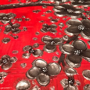 May include: A red background with a silver and black floral design. The flowers are painted in a textured style, giving the appearance of 3D.