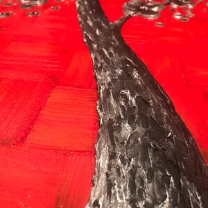 May include: A close-up of a black tree trunk with a textured surface against a red background. The tree is painted in a stylized manner with silver accents.