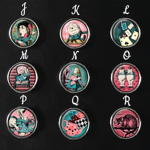Può includere: Set di 10 cabochon rotondi in vetro, rosa e bianchi, a tema Alice nel Paese delle Meraviglie. Ogni cabochon presenta un personaggio o una scena diversa dal libro, tra cui il Cappellaio Matto, la Regina di Cuori e Alice stessa.