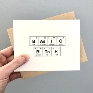 Puede incluir: Una tarjeta blanca con un diseño de tabla periódica en blanco y negro. Los elementos están dispuestos para deletrear la palabra "BASIC" en la fila superior y "BITCH" en la fila inferior.