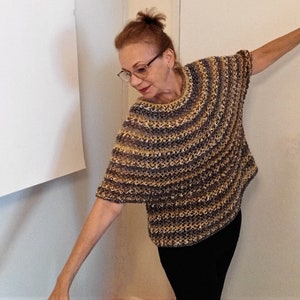 May include: A woman wearing a striped knit top with a loose, flowing fit. The top is a mix of brown, beige, and gray colors. The woman is wearing black pants and has her hair pulled back in a ponytail.