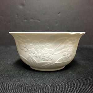 May include: White ceramic bowl with a floral design. The bowl has a slightly scalloped rim and a smooth, glossy finish.