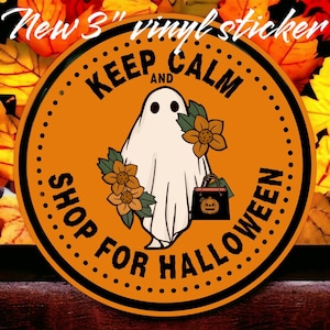 May include: A 3-inch vinyl sticker with a Halloween theme. The sticker features a white ghost with black eyes, holding a shopping bag with a jack-o'-lantern design. The text reads "KEEP CALM AND SHOP FOR HALLOWEEN" in black on an orange background.
