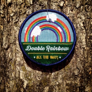 May include: A blue and green embroidered patch with a double rainbow and the text "Double Rainbow All The Way!"
