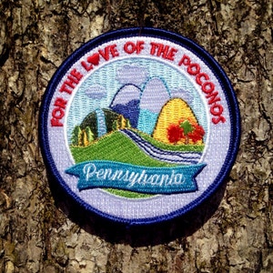 May include: A blue and white embroidered patch with the text "For the Love of the Poconos Pennsylvania". The patch features a stylized landscape with mountains, a river, and trees.