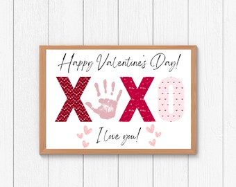 May include: A white printable sign with a red and pink heart pattern. The sign says "Happy Valentine's Day!" and "XOXO" with a pink handprint in the middle. The sign also says "I love you!" with pink hearts around the text.