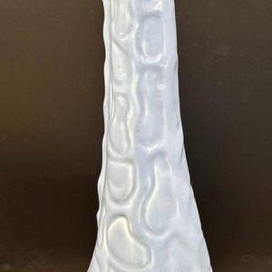 May include: A light blue ceramic giraffe figurine. The giraffe has a textured body and a long neck. The figurine is approximately 12 inches tall. The giraffe is a decorative item.